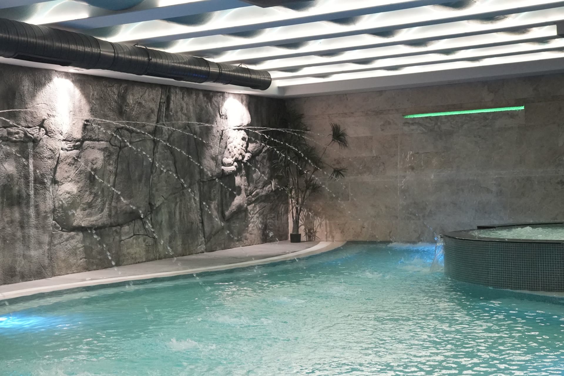 The spa pool with water jets arcing from a rock wall